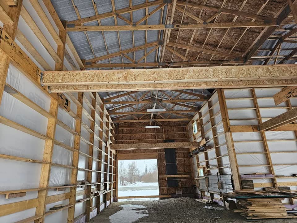 Interior framing view of 24x64x20 post frame shop with 29 gauge steel and weather barrier in Morris Illinois