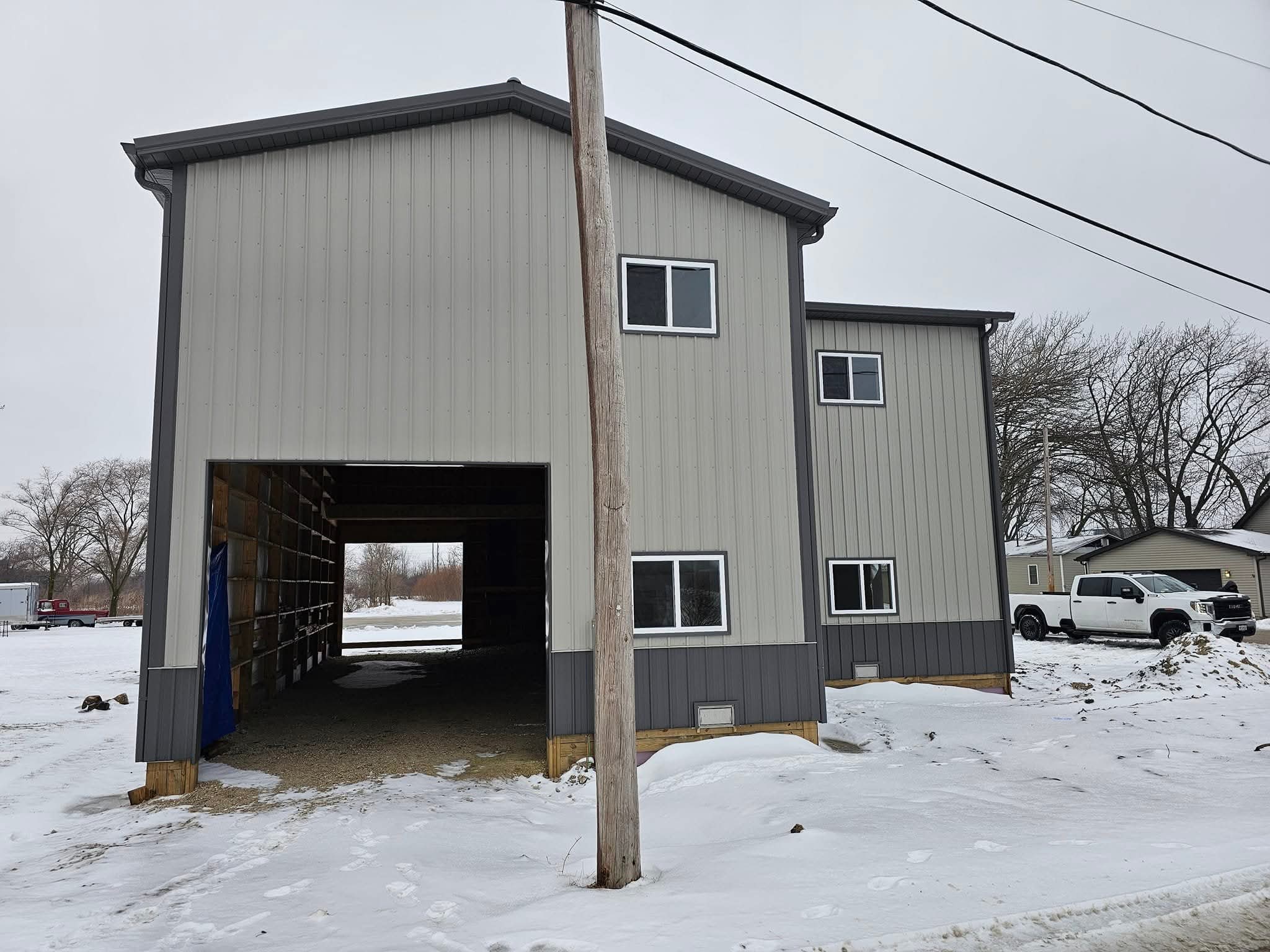 Side angle view of 24x64x20 post frame shop with charcoal and smoke gray steel exterior in Morris Illinois